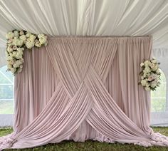 an image of a wedding ceremony setting with flowers on the back wall and draping