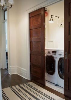 a washer and dryer sitting in front of a doorway with a rug on the floor