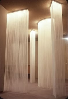 two tall white curtains are hanging from the ceiling in a room with carpeted flooring