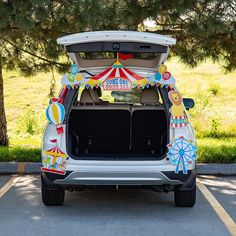 the back end of a white car with an open trunk and circus decorations on it