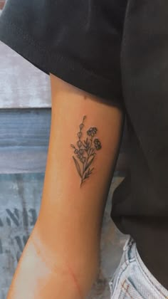 a small flower tattoo on the left inner arm and wrist, with an arrow in the center