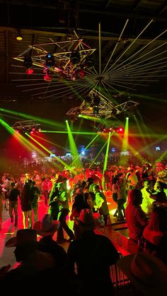 a group of people standing on top of a dance floor under bright colored lights at night