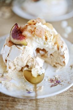 a white plate topped with ice cream covered in toppings and a gold spoon sitting on top of it