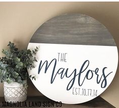 a wooden sign that says the mayfoss on it next to a potted plant