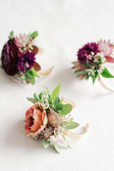 three bouquets of flowers sitting on top of a white table