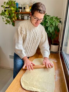 a man rolling dough on top of a wooden counter