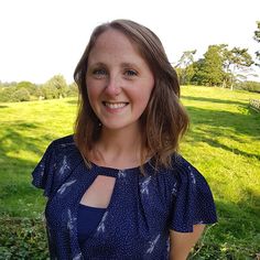 a woman standing in front of a lush green field