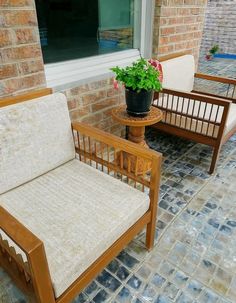 two wooden chairs sitting next to each other in front of a brick building with a potted plant