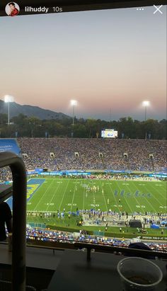 a football stadium filled with lots of people watching the game at sunset or sunrise time