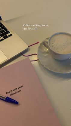 a cup of coffee sitting on top of a table next to a notebook and pen