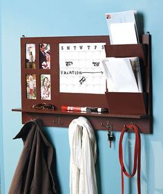 a brown bulletin board mounted to the side of a wall next to a coat rack