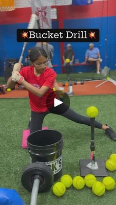 a woman is hitting tennis balls with a racket and some buckets on the ground