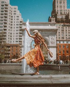 a woman is dancing in front of a fountain