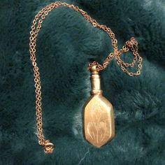 a gold necklace with a bottle shaped like a dandelion hanging from it's chain