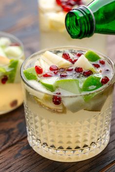 a glass filled with fruit and ice on top of a wooden table