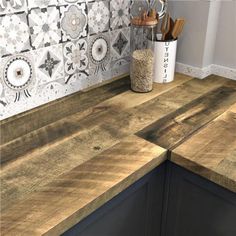 a wooden counter top in a kitchen next to a vase with utensils on it