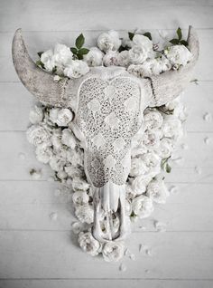 a white cow skull with flowers on it's head is shown in front of a wooden wall