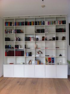 a white book shelf filled with lots of books on top of a hard wood floor