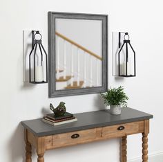 a mirror on the wall above a table with a potted plant next to it