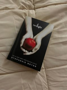 there is a book on the bed that has an apple in its hand and it says twilight