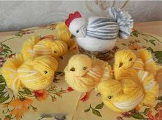 several small yellow chickens sitting on top of a flowered table cloth with yarn wrapped around them