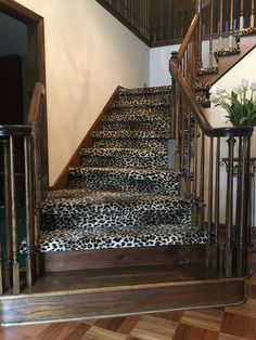 a staircase with leopard print carpet and wooden handrails