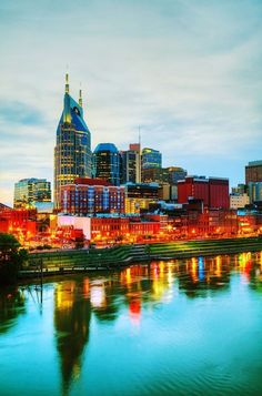 the city is lit up at night with lights reflecting in the water and buildings on both sides