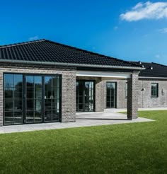 a brick building with glass doors and windows on the outside, in front of green grass