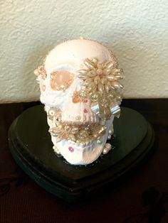 a white skull sitting on top of a black stand with pearls and jewels around it