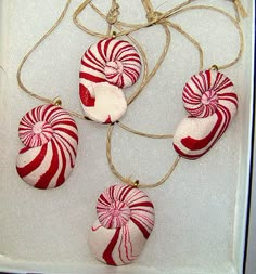 three red and white candy canes are hanging from a string in a gift box