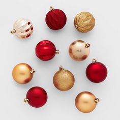 an assortment of christmas ornaments arranged on a white surface, including red and gold baubles