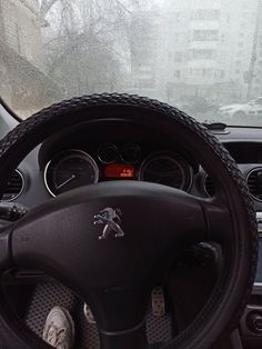 the steering wheel and dashboard of a car with snow on the ground in the background