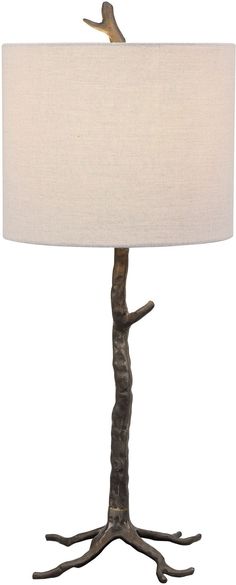 a bird perched on top of a tree branch table lamp with a white linen shade