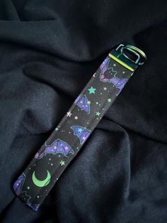 an apple watch band with bat and stars on it, sitting on a black cloth