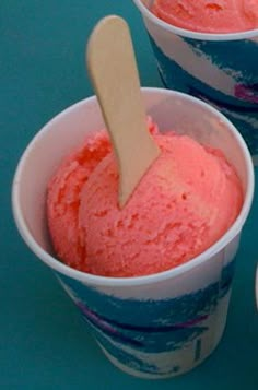 three ice cream cups with spoons in them on a blue tableclothed surface