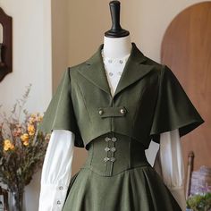 a green dress with buttons on the front and collared neckline, sitting on a mannequin