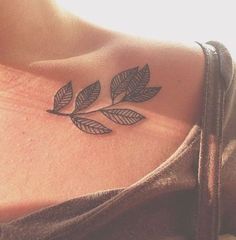 a woman with a tattoo on her chest has leaves in the shape of a leaf