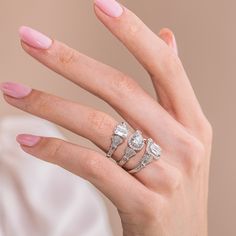 a woman's hand with three rings on her fingers and pink manicured nails