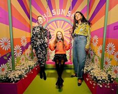 three women standing in front of a colorful backdrop