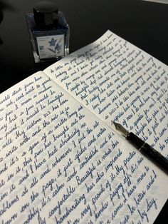 a pen sitting on top of a piece of paper next to a small ink bottle