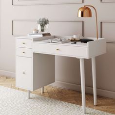 a white desk with two drawers and a lamp on the top, in front of a beige wall