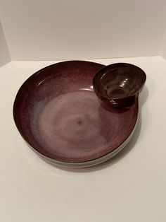 a purple plate with a spoon on it sitting on a white counter top next to a wall