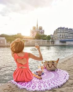 a woman is sitting on the beach and enjoying her meal with a view of paris