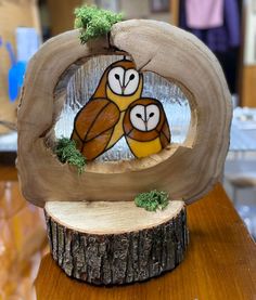 two owls sitting on top of a piece of wood