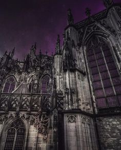 an old gothic building with purple sky in the background