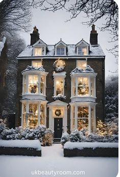 a large house covered in snow with christmas lights on the windows and wreaths hanging from the roof