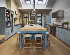 a large kitchen with blue cabinets and wooden counter tops, along with two bar stools