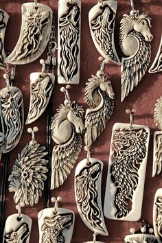 many different types of pendants are hanging on a red wall together with other necklaces