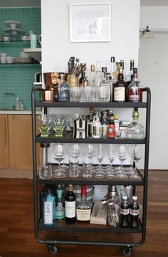 a bar cart filled with lots of bottles and glasses on top of a hard wood floor