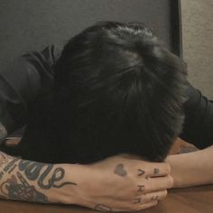 a man with tattoos covering his face sitting at a table